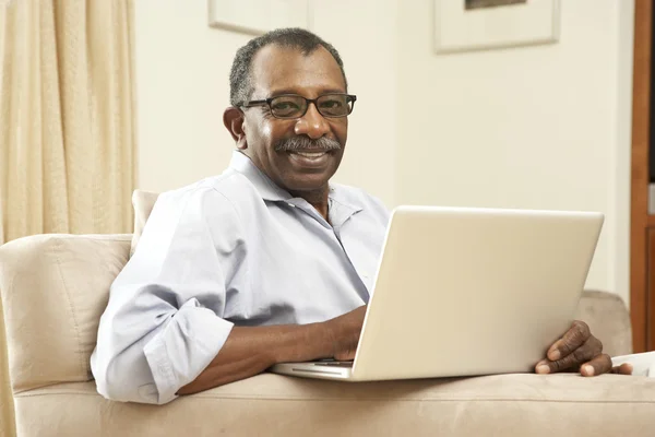 Senior man met laptop thuis — Stockfoto