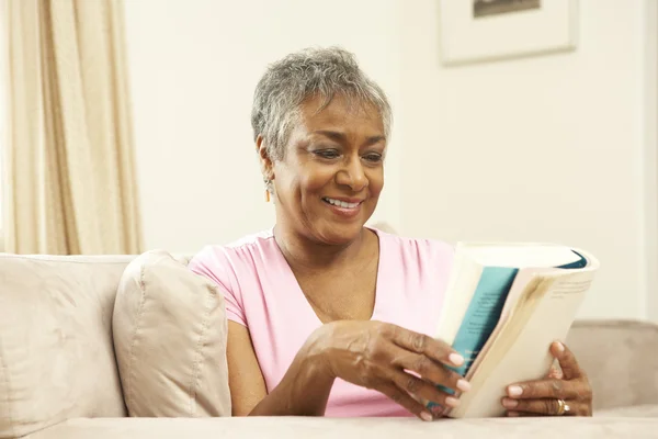 Senior kvinna läser bok hemma — Stockfoto