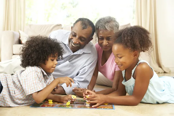 Abuelos jugando juego de mesa en casa con nietos — Foto de Stock