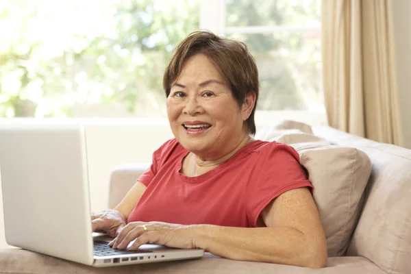 Ηλικιωμένη γυναίκα που χρησιμοποιεί φορητό υπολογιστή στο σπίτι — Φωτογραφία Αρχείου