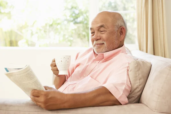 年配の男性人自宅でドリンクを飲みながら本を読んで — ストック写真