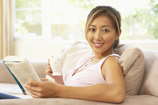 Vrouw lezen boek met drankje thuis — Stockfoto