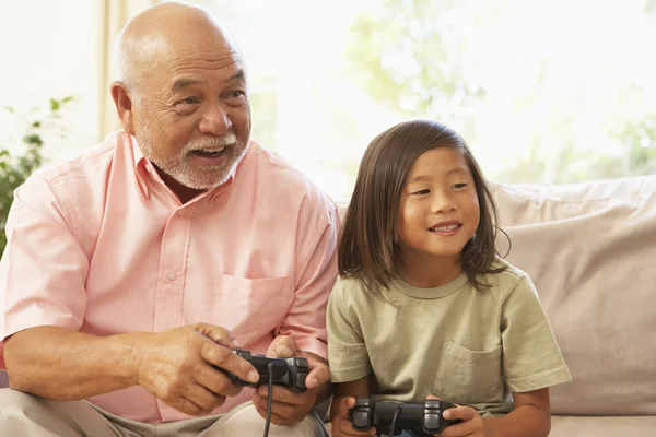 Дедушка и внук играют в компьютерные игры дома — стоковое фото