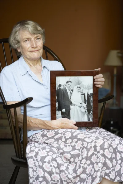 Anziana donna a casa guardando vecchio matrimonio foto — Foto Stock