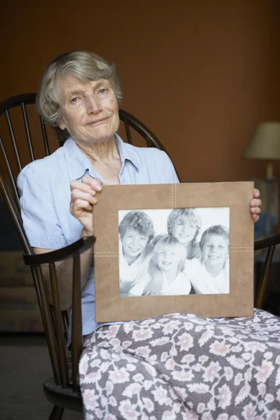 Senior Woman Home Looking Photo Grandchildren — Stock Photo, Image
