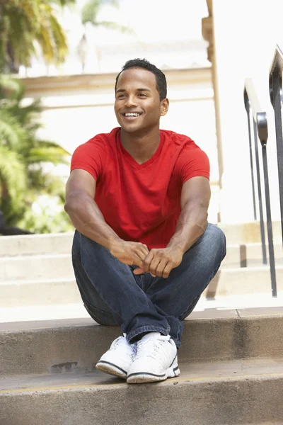 Młody mężczyzna siedzący na schodach budynku — Zdjęcie stockowe
