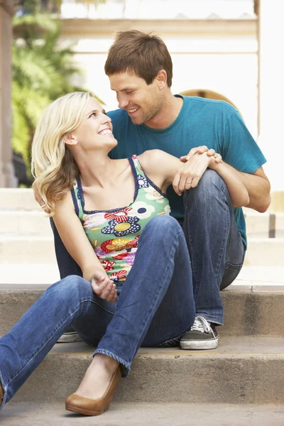 Молодая пара, сидящая на ступенях здания — стоковое фото