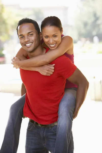 Jovem homem dando mulher piggyback ao ar livre — Fotografia de Stock