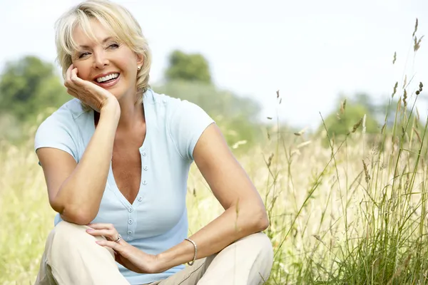 Portrait of mature woman sitting in countryside Stock Photo