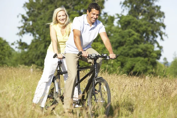 Couple riding tandem in countryside Royalty Free Stock Images