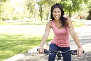 Young Woman Riding Bike In Park clipart