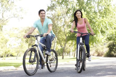Young Couple Riding Bike In Park clipart