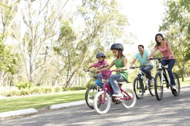 Young Family Riding Bikes In Park clipart