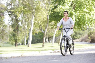 Senior Woman Cycling In Park clipart