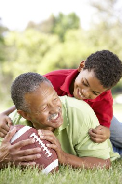 Grandfather With Grandson In Park With American Football clipart