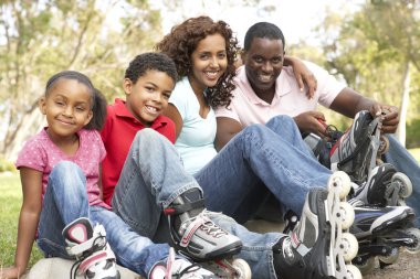 Family Putting On In Line Skates In Park clipart