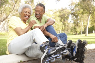 Senior Couple Putting On In Line Skates In Park clipart