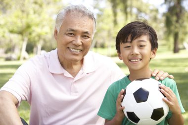 Grandfather And grandson In Park With Football clipart