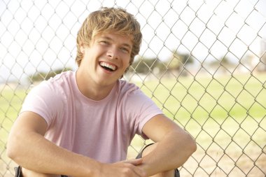 Teenage Boy Sitting In Playground clipart