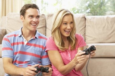 Young Couple Playing Computer Game On Sofa At Home clipart