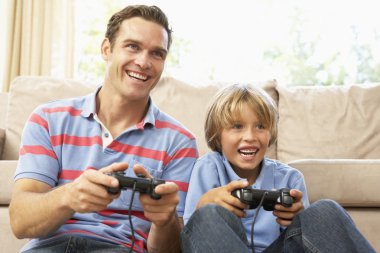 Father And Son Playing Computer Game On Sofa At Home clipart