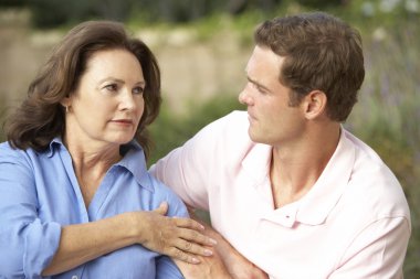 Senior Woman Being Comforted By Adult Son clipart