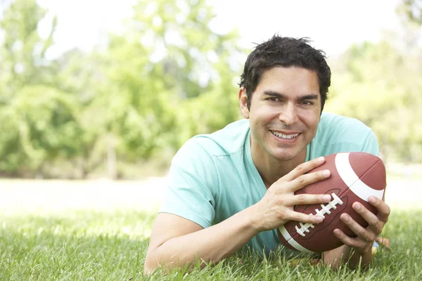 Porträtt av ung man i parken med amerikansk fotboll — Stockfoto