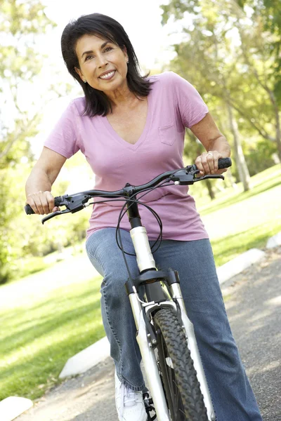 Senior vrouw rijden fiets in park — Stockfoto
