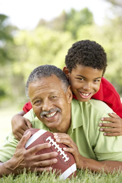 Дедушка с внуком в парке с американским футболом — стоковое фото