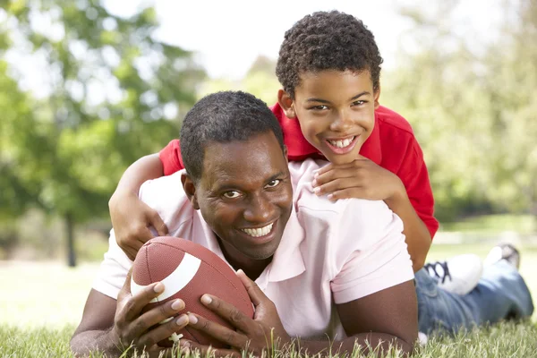 Far och son i park med amerikansk fotboll — Stockfoto