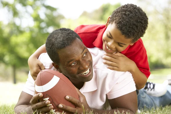 Отец и сын в парке с американским футболом — стоковое фото