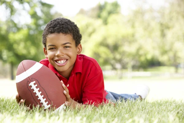 Мальчик в парке с американским футболом — стоковое фото
