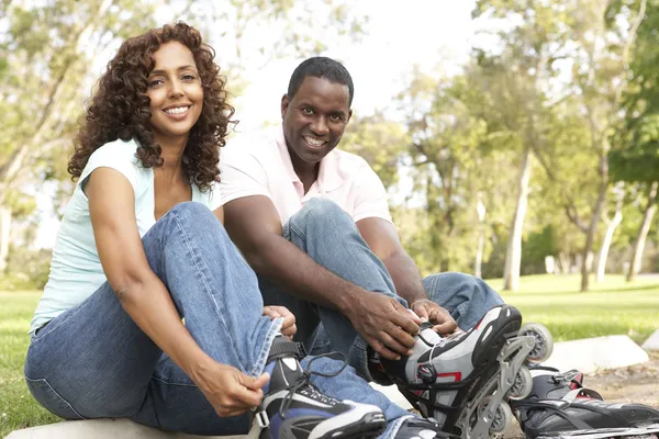 Par att sätta på i line skridskor i park — Stockfoto