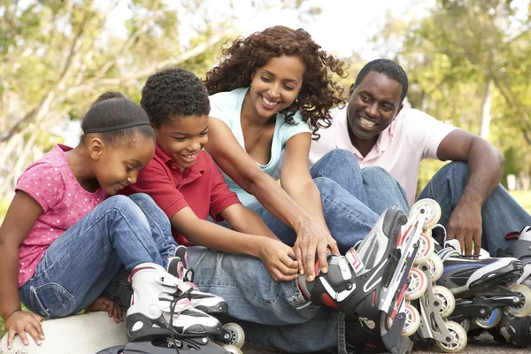 Famille mettant dans les patins à roues alignées dans le parc — Photo