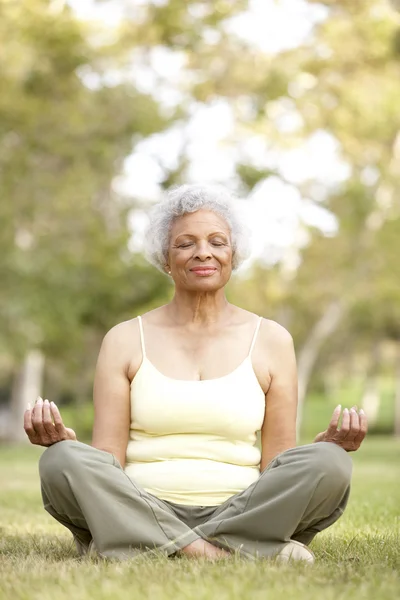 Äldre kvinna gör yoga i park — Stockfoto