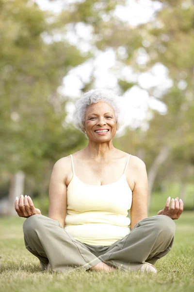 Senior vrouw doen yoga in park — Stockfoto