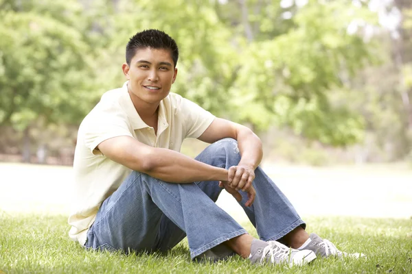 Portret van een jonge man zit in park — Stockfoto