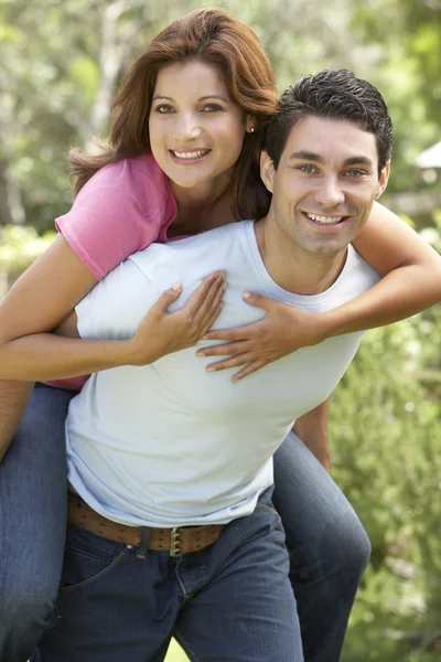 Jonge man geven vrouw piggyback buitenshuis — Stockfoto