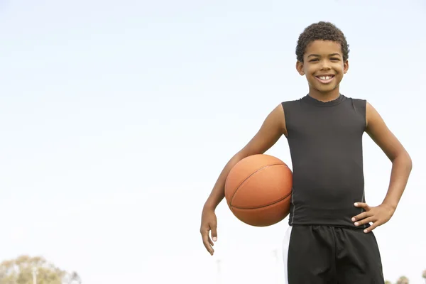 Młody chłopiec gra w koszykówkę — Zdjęcie stockowe