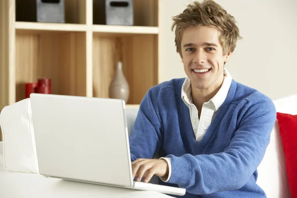 Genç adam evde dizüstü bilgisayar kullanıyor. — Stok fotoğraf