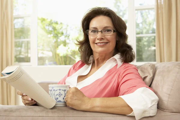 Mujer mayor leyendo libro con bebida en casa —  Fotos de Stock