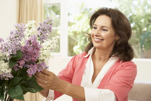 年配の女性が自宅で花を生ける — ストック写真