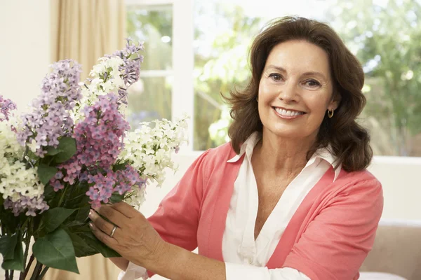 Senior vrouw thuis schikken van bloemen — Stockfoto