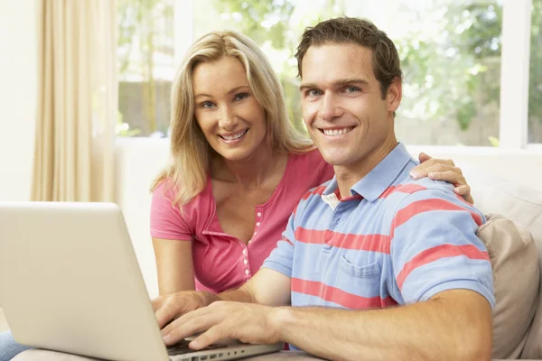 Молодая пара использует ноутбук дома — стоковое фото