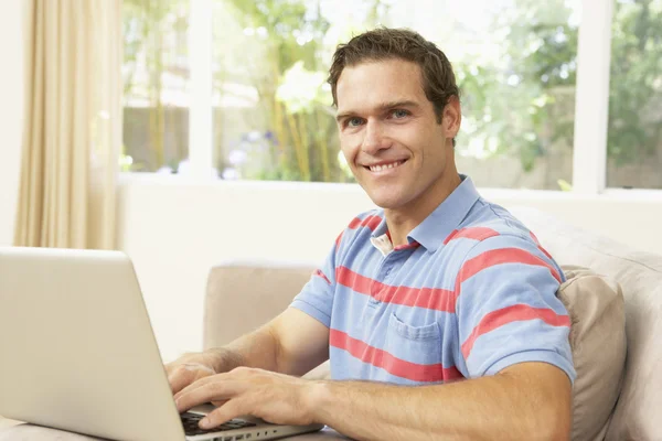 Genç adam evde dizüstü bilgisayar kullanıyor. — Stok fotoğraf