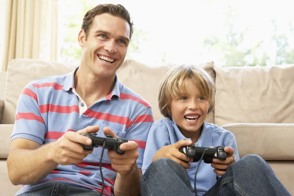 Отец и сын играют в компьютерные игры на диване дома — стоковое фото