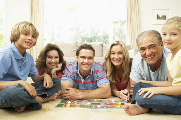 Familj spelar brädspel hemma med mor-och farföräldrar tittar — Stockfoto