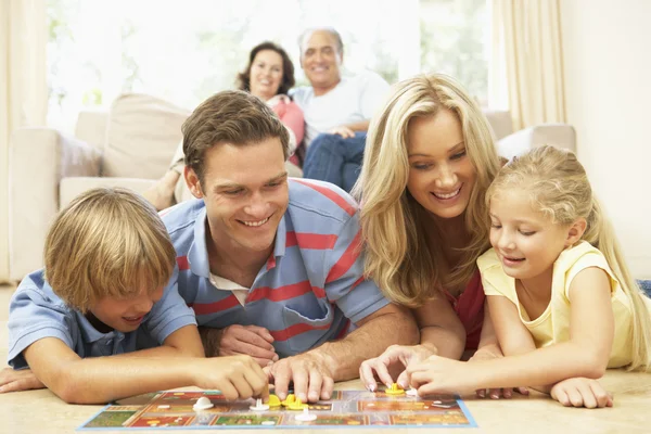 Familj spelar brädspel hemma med mor-och farföräldrar tittar — Stockfoto