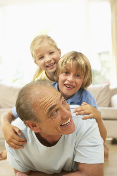 Дедушка играет с внуками дома — стоковое фото