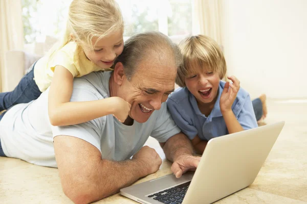 Дедушка и внуки используют ноутбук дома — стоковое фото
